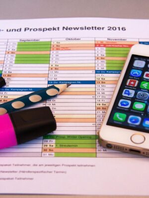 A desk setup featuring a planner, pens, and a smartphone displaying app icons, ideal for productivity.