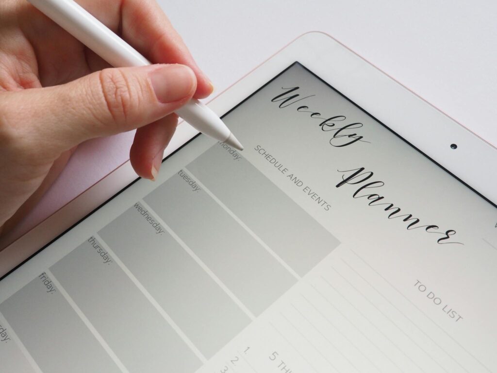 The Essentials of Blogging: Tips and Strategies for Success A stylus writing in a digital weekly planner on a tablet screen, ideal for organization.