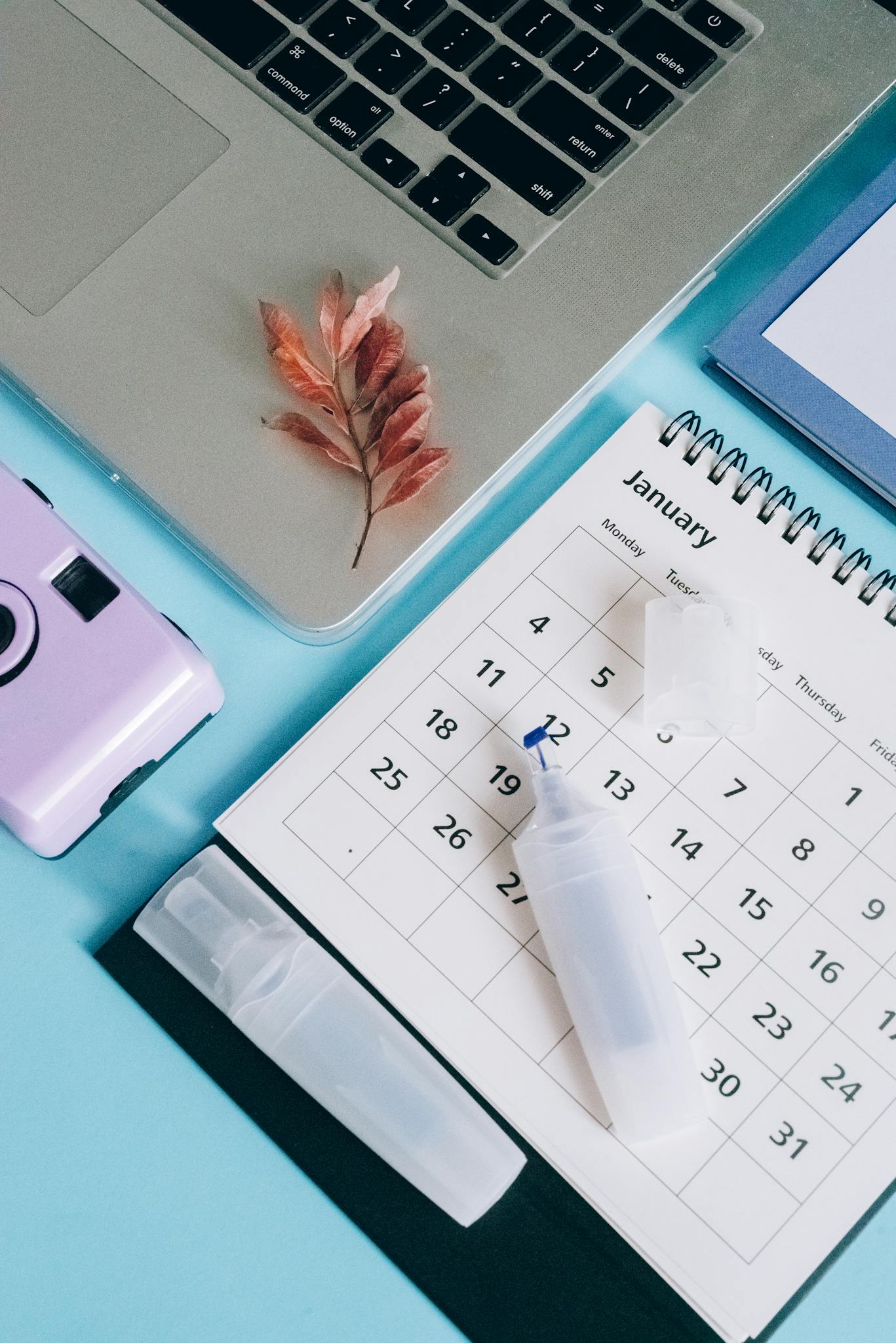 Flat lay of a calendar, laptop, and creative tools, perfect for planning inspiration.